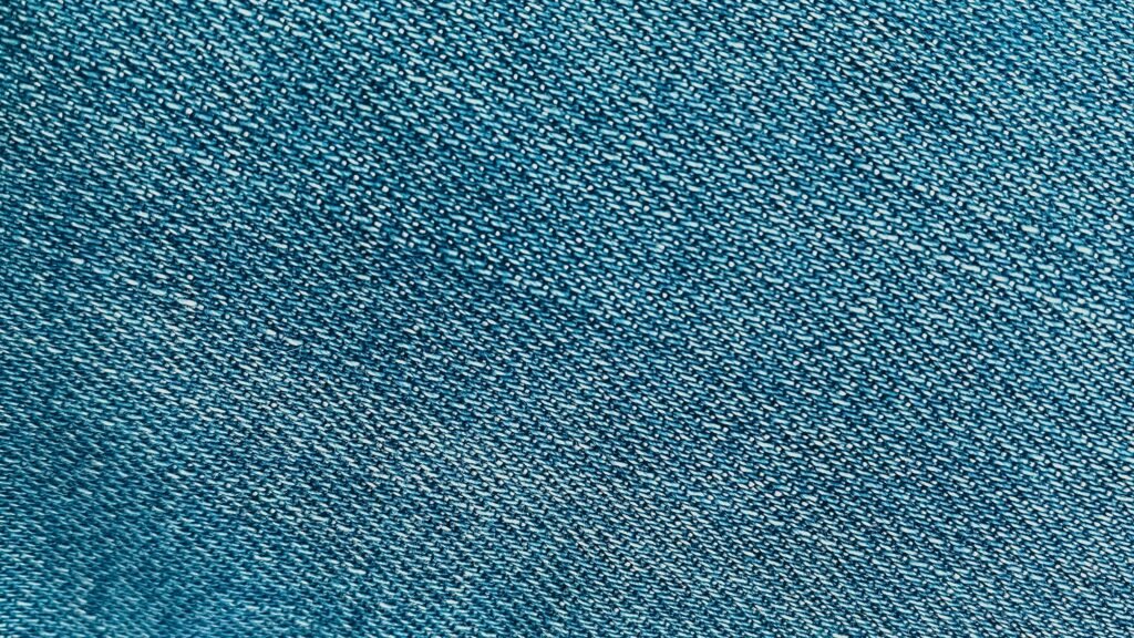 Home Detailed close-up of the textured surface of blue denim fabric.